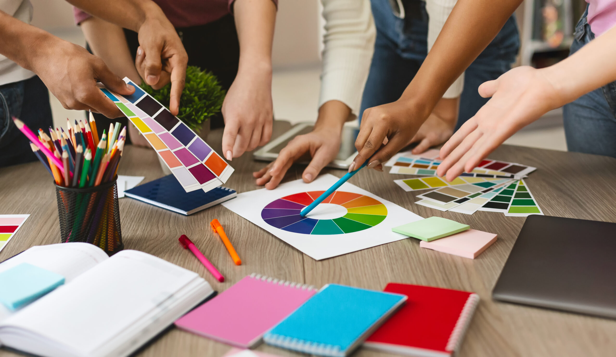 Creative multi ethnic graphic designers choosing color swatch samples for selection coloring, working with new project, close up - photo for nonprofit style guide illustration