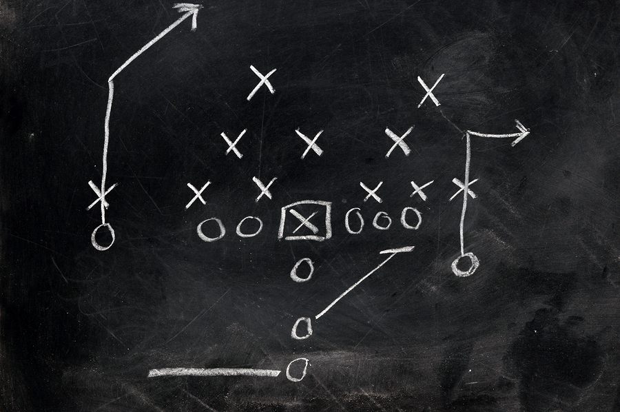 Diagram of football play on black chalkboard.