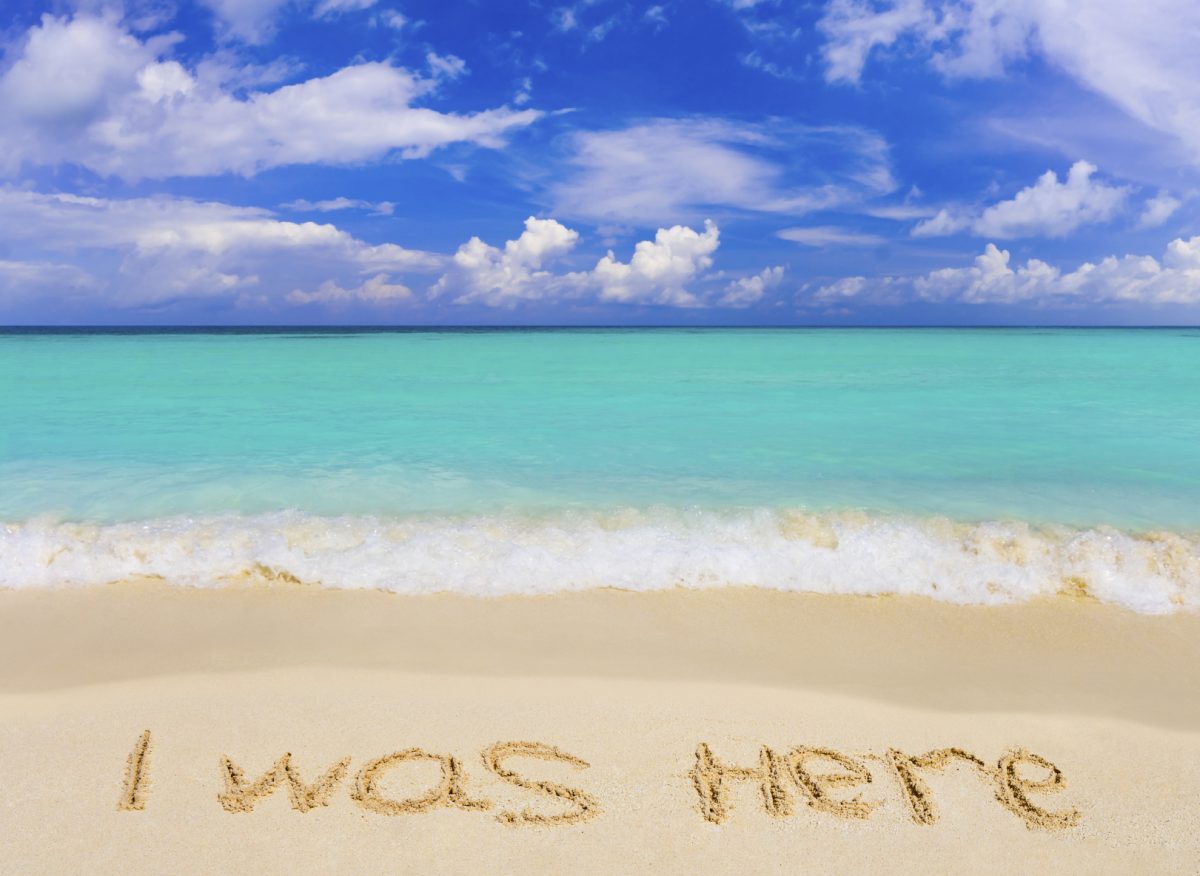 Beach with writing in sand saying, "I was here."