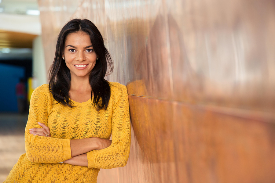 Portrait of a cheerful attractive businesswoman standing with ar