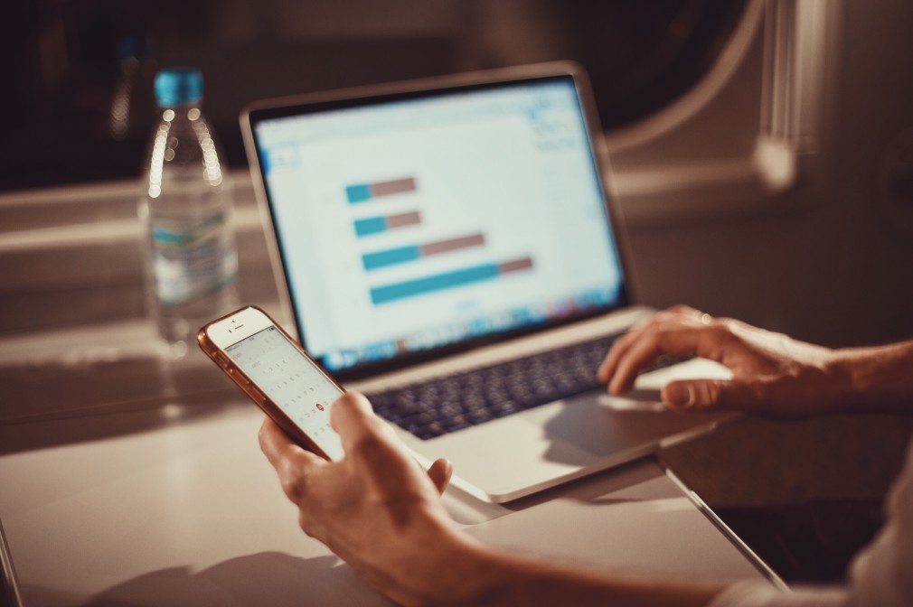 person on a phone and laptop on a desk