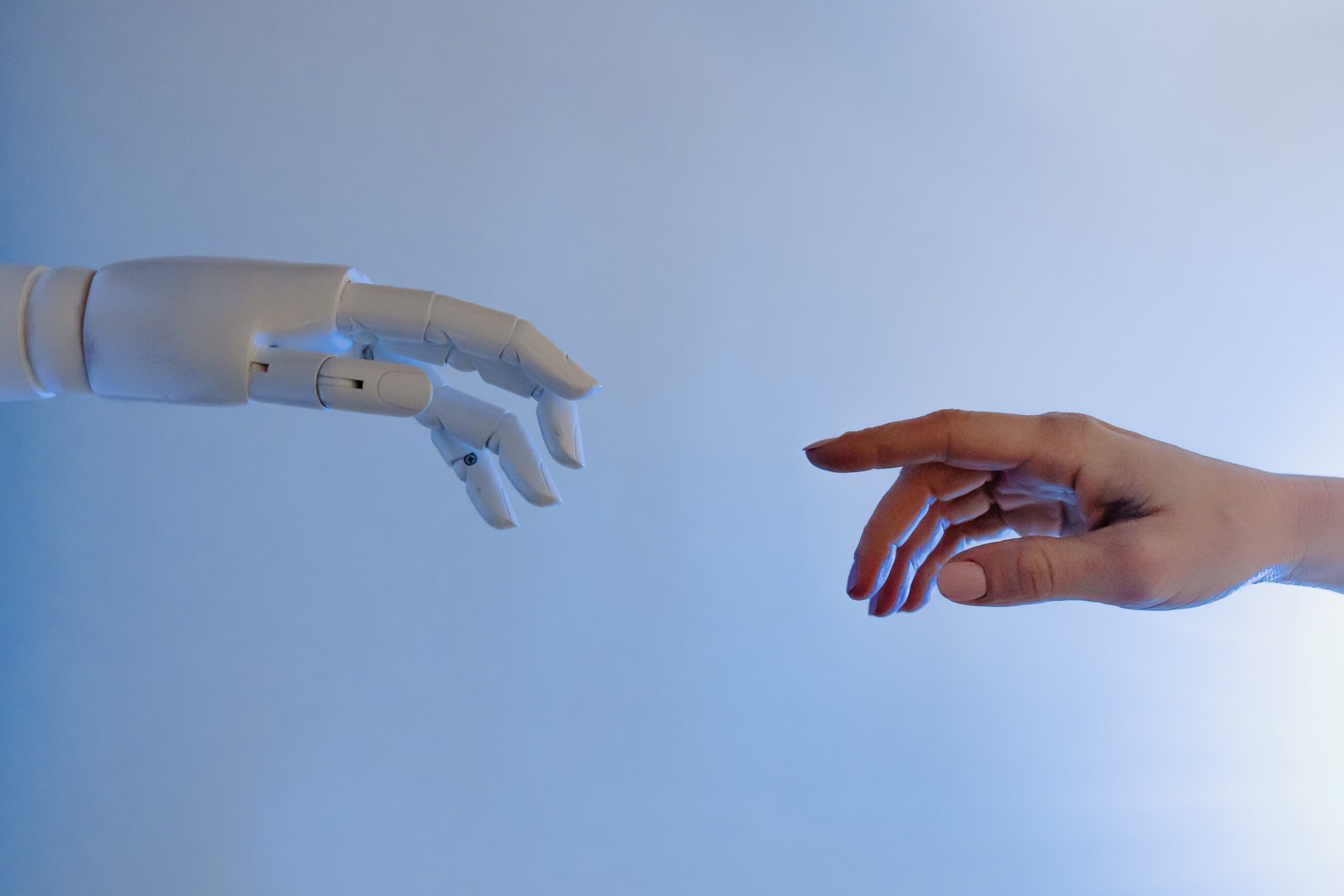 robot hand and human hand almost touching mid-air